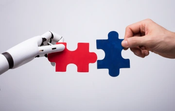 Robot and human hands holding puzzle pieces